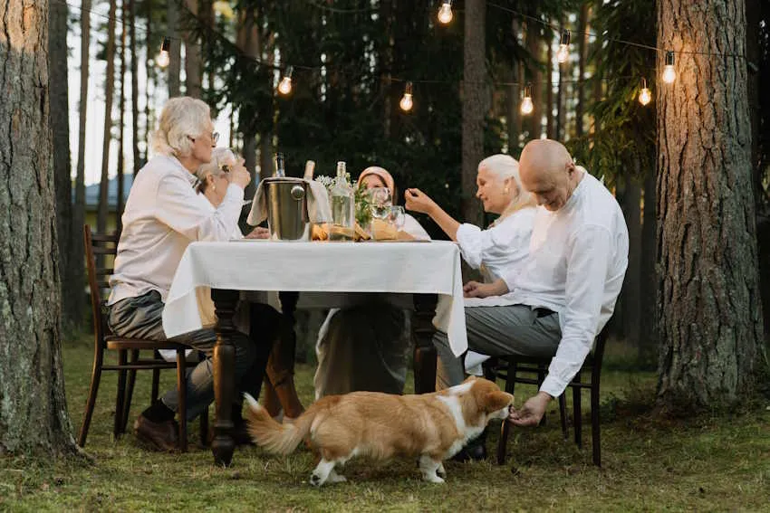 des personnes âgées sont à table et un homme donne à manger à un corgi sous la nappe